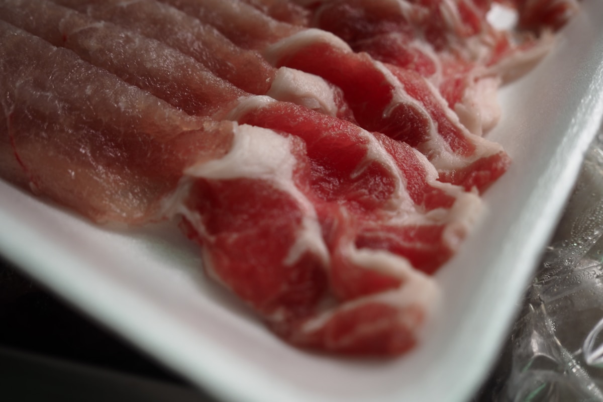 白いトレイの薄切り豚肉のアップ。赤身と白い脂のコントラストがわかる