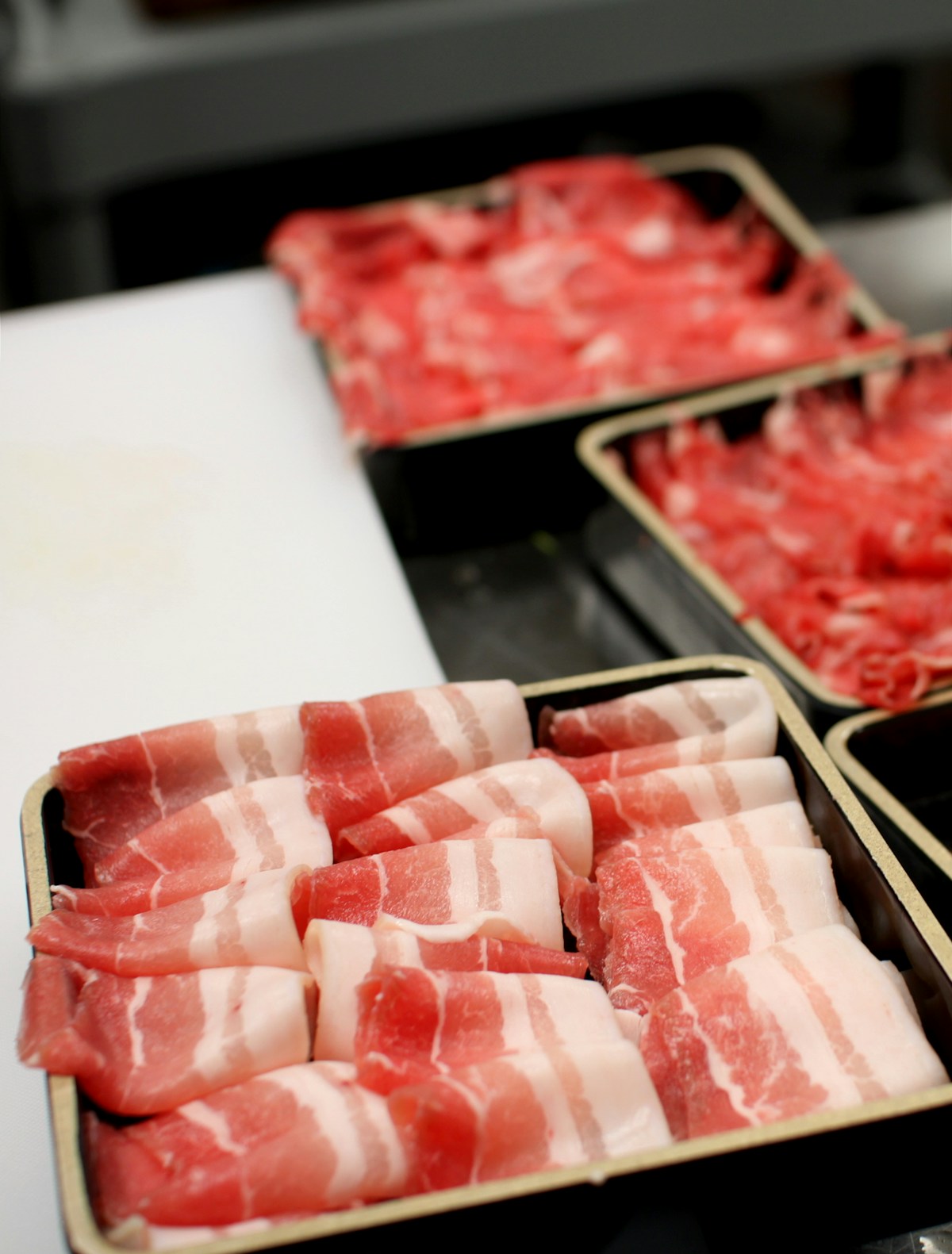 全体が淡いピンク色でそろった薄切り豚肉のトレイ
