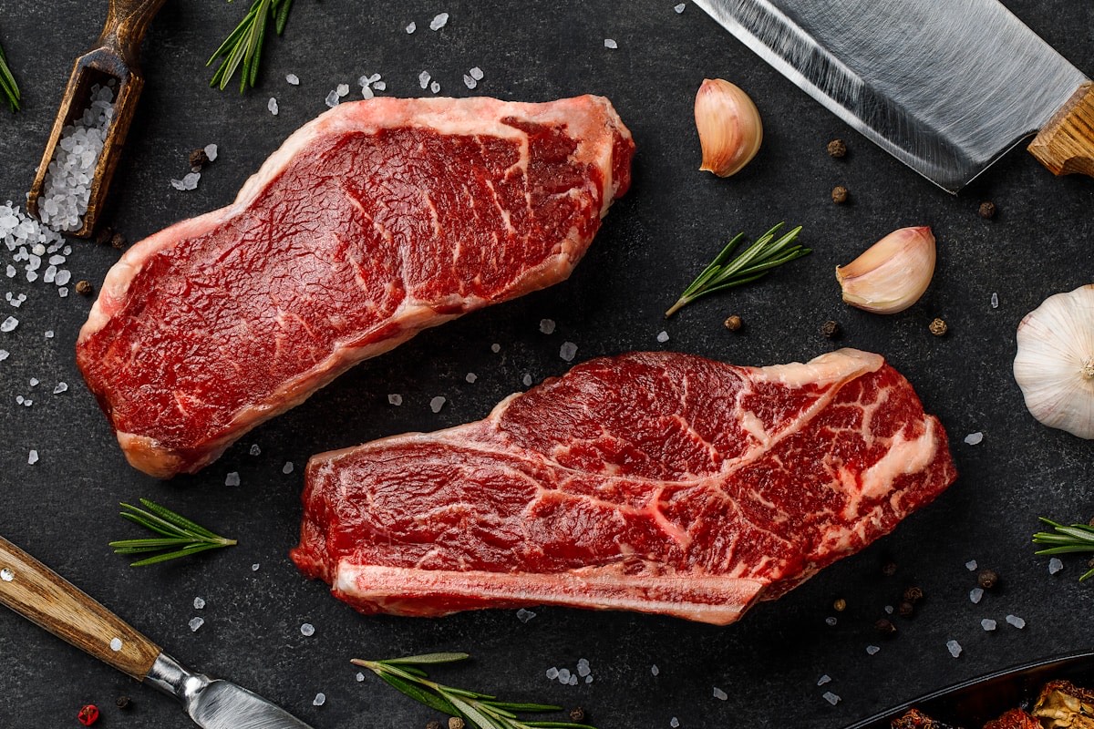 まな板の上に置かれた厚切りの生ステーキ肉2枚